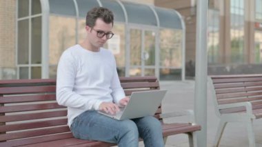 Coughing Casual Man Using Laptop while Sitting Outdoor on Bench