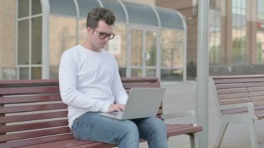 Rejecting Casual Man in Denial While using Laptop Sitting Outdoor on Bench 