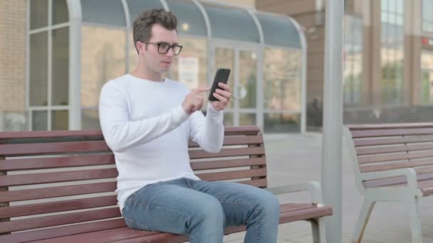 Casual Man Celebrating Online Success Smartphone While Sitting Outdoor Bench — Stockvideo