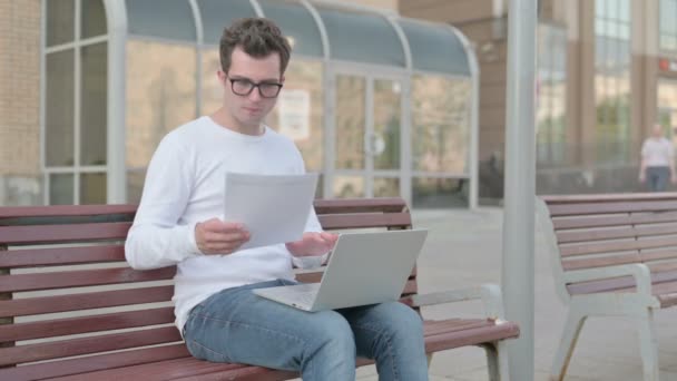 Casual Man Reading Documents Working Laptop While Sitting Bench Outdoor — стоковое видео