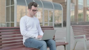 Thinking Casual Man Using Laptop while Sitting Outdoor on Bench