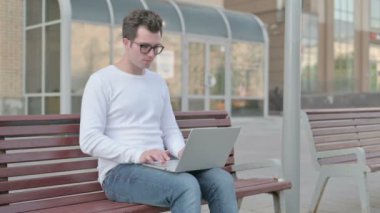 Casual Man Reacting to Loss on Laptop while Sitting Outdoor on Bench