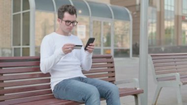 Casual Man Reacting to Online Payment Failure on Smartphone while Sitting Outdoor on Bench