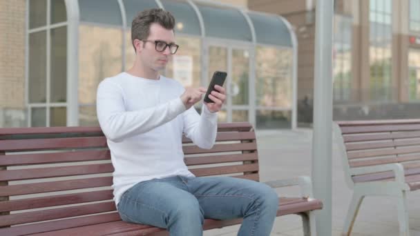 Casual Man Using Smartphone While Sitting Outdoor Bench — Stockvideo