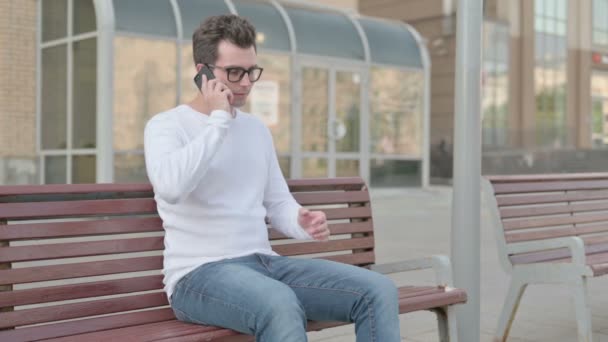 Angry Casual Man Talking Phone While Sitting Outdoor Bench — Vídeos de Stock
