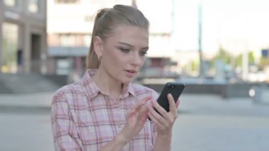 Casual Woman Celebrating Online Success on Smartphone Outdoor