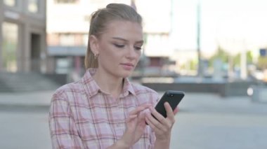 Casual Woman Browsing Internet on Smartphone Outdoor