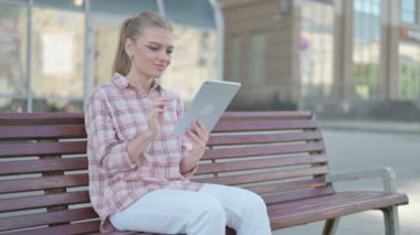 Online Video Chat on Tablet by Casual Woman Sitting Outdoor on Bench 