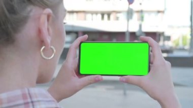 Close Up of Casual Woman Holding Horizontal Smartphone with Green Screen Outdoor