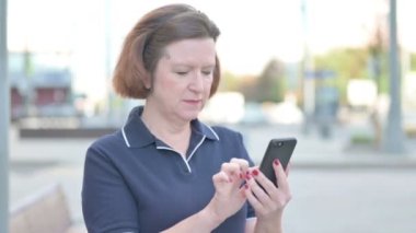 Senior Old Woman Celebrating Win on Smartphone Outdoor