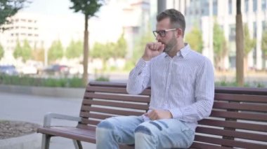 Adult Man Coughing while Sitting on Bench Outdoor
