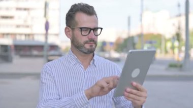 Adult Man Celebrating Success on Tablet Outdoor