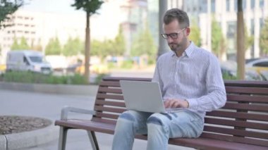 Adult Man with Laptop Showing Thumbs Up Sign While Sitting Outdoor on Bench 