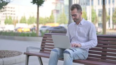 Adult Man with Laptop Smiling at Camera while Sitting Outdoor on Bench