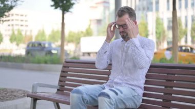 Adult Man with Headache Sitting Outdoor on Bench