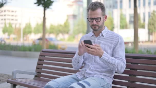 Adult Man Reacting Loss Smartphone While Sitting Outdoor Bench — Stockvideo