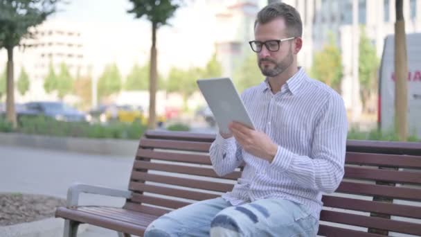 Adult Man Using Tablet While Sitting Outdoor Bench — Stockvideo