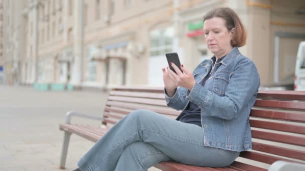 Senior Old Woman Reacting Loss Smartphone While Sitting Outdoor Bench — Vídeo de stock