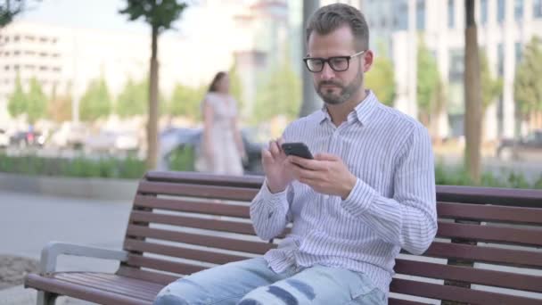 Adult Man Celebrating Online Success Smartphone While Sitting Outdoor Bench — Wideo stockowe