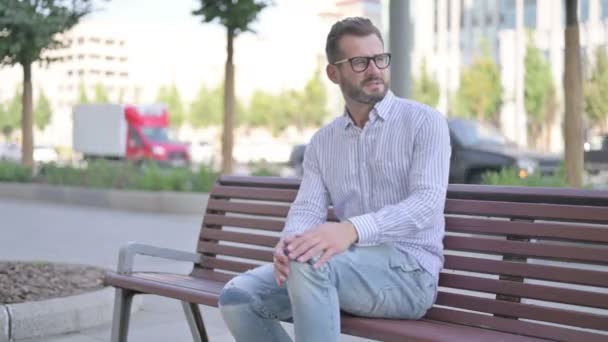 Adult Man Having Knee Pain While Sitting Bench Outdoor — Wideo stockowe