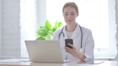 Klinikte dizüstü bilgisayar kullanırken Smartphone kullanan kadın doktor 