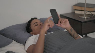The Young African Woman using Smartphone while Sleeping in Bed