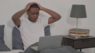 The Young African Man Reacting to Loss on Laptop in Bed