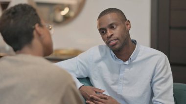 The Serious Young African Woman Talking to African Man on Sofa