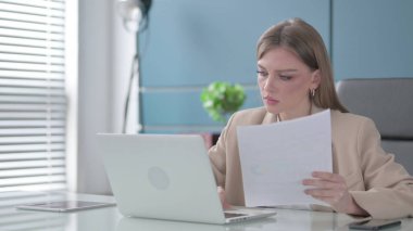 Dizüstü bilgisayar kullanırken Genç İş Kadını Raporları Okuyor