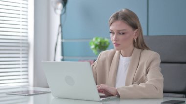 Ofisteki dizüstü bilgisayarda çalışan genç iş kadını