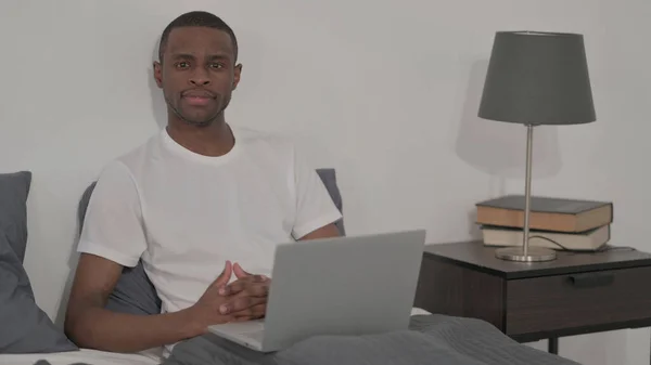 Young African Man Looking Camera While Using Laptop Bed — Fotografia de Stock