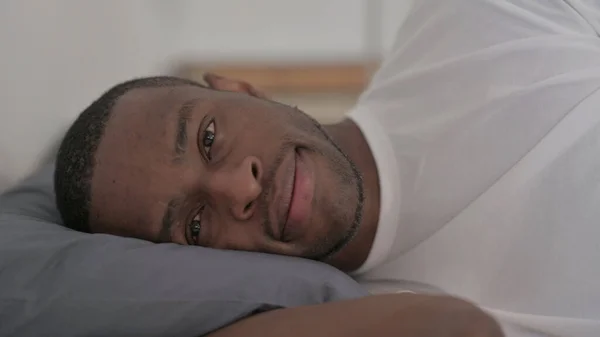 Smiling Young African Man Laying Bed Awake Thinking — Fotografia de Stock