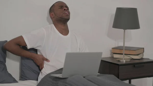 Young African Man Back Pain Working Laptop Bed — Fotografia de Stock