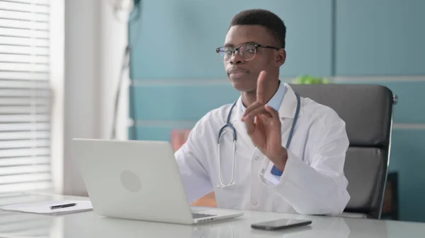 African Doctor Shaking Head as No Sign while using Laptop in Office