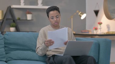 The Young African Woman with Laptop Working on Documents on Sofa