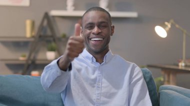 The Portrait of African Man Showing Thumbs Up while Sitting on Sofa