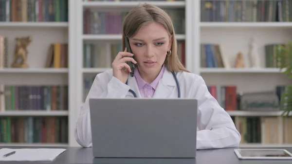 Female Doctor Talking Phone While Using Laptop Clinic — Stockfoto