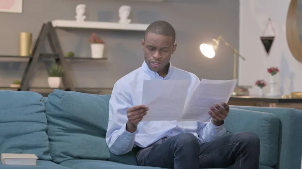 The Young African Man Reading Reports while Sitting on Sofa