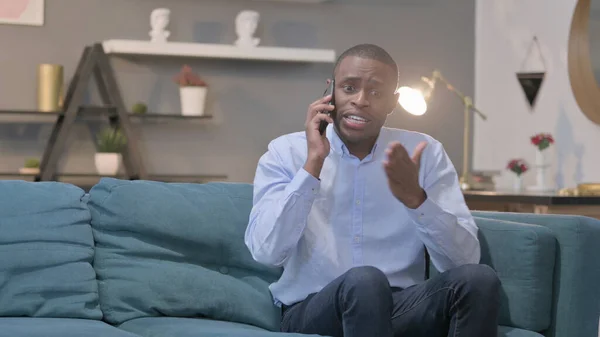 Angry Young African Man Talking Smartphone Sofa —  Fotos de Stock