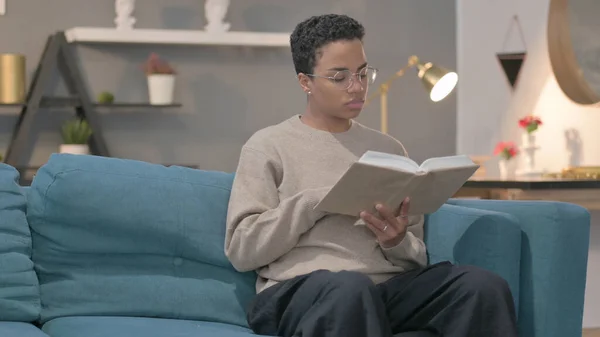 Young African Woman Reading Book While Sitting Sofa — 스톡 사진