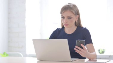 Laptop kullanırken Smartphone kullanan Genç Kadın