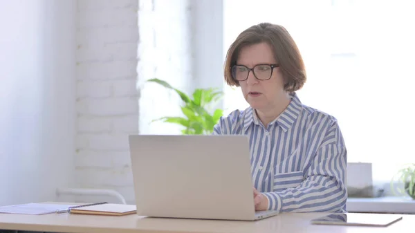 Angry Old Woman Working on Laptop in Office
