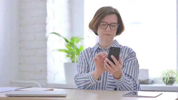 Old Woman using Smartphone in Office