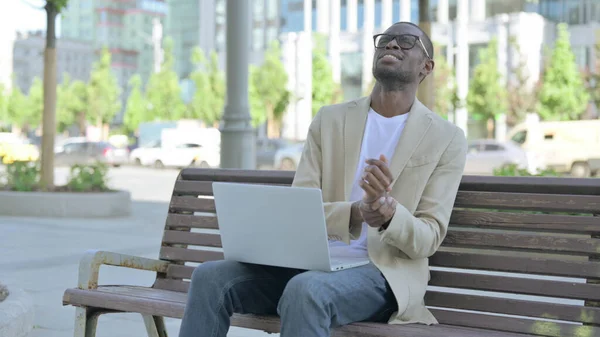 African American Man with Neck Pain Using Laptop while Sitting Outdoor on Bench