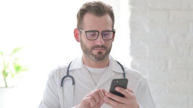 Orta yaşlı doktor akıllı telefon kullanıyor.