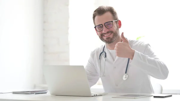 Middle Aged Doctor Showing Thumbs Sign While Using Laptop Clinic — Φωτογραφία Αρχείου