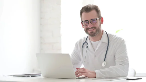 Middle Aged Doctor with Laptop Shaking Head as Yes Sign