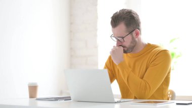 Ofiste dizüstü bilgisayar kullanırken orta yaşlı adam öksürüyor