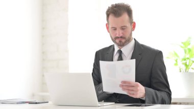 Ofiste Dizüstü bilgisayarlı İşadamı Okuma Belgeleri