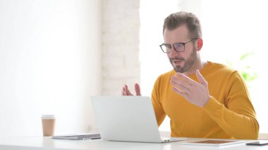 Ofiste dizüstü bilgisayar kullanırken Orta Yaşlı Adam Başarı Kutlaması